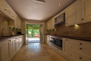 A kitchen with white cabinets, a stone backsplash, and a view to an outdoor deck.