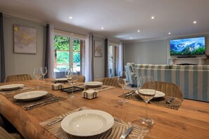 A dining area with a wooden table set for a meal, a television, and a view of greenery outside. - Villa Gageac - 6 people - Upscale - Sarlat / Roque Gageac (24) (La Roque-Gageac)