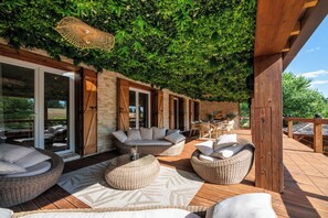 Ein Außenbereich mit Korbmöbeln, einer Holzterrasse und einer grünen Wand.