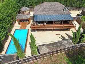 A large house with a swimming pool, a covered deck area, and a fenced yard.