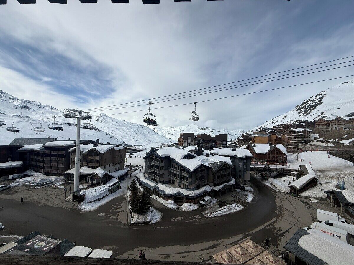Ein Skigebiet mit mehreren Gebäuden, einer Seilbahn und verschneiter Landschaft.