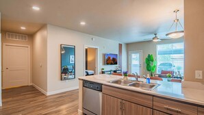 A modern kitchen with a dishwasher, double sink, and wooden cabinets. - Tempe DT Escape | Pool, Gym, W/D, Parking Sleeps 4 (Tempe)