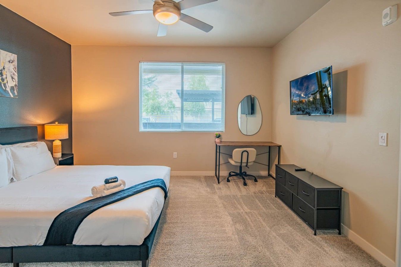 A bedroom with a bed, desk, chair, and a ceiling fan.