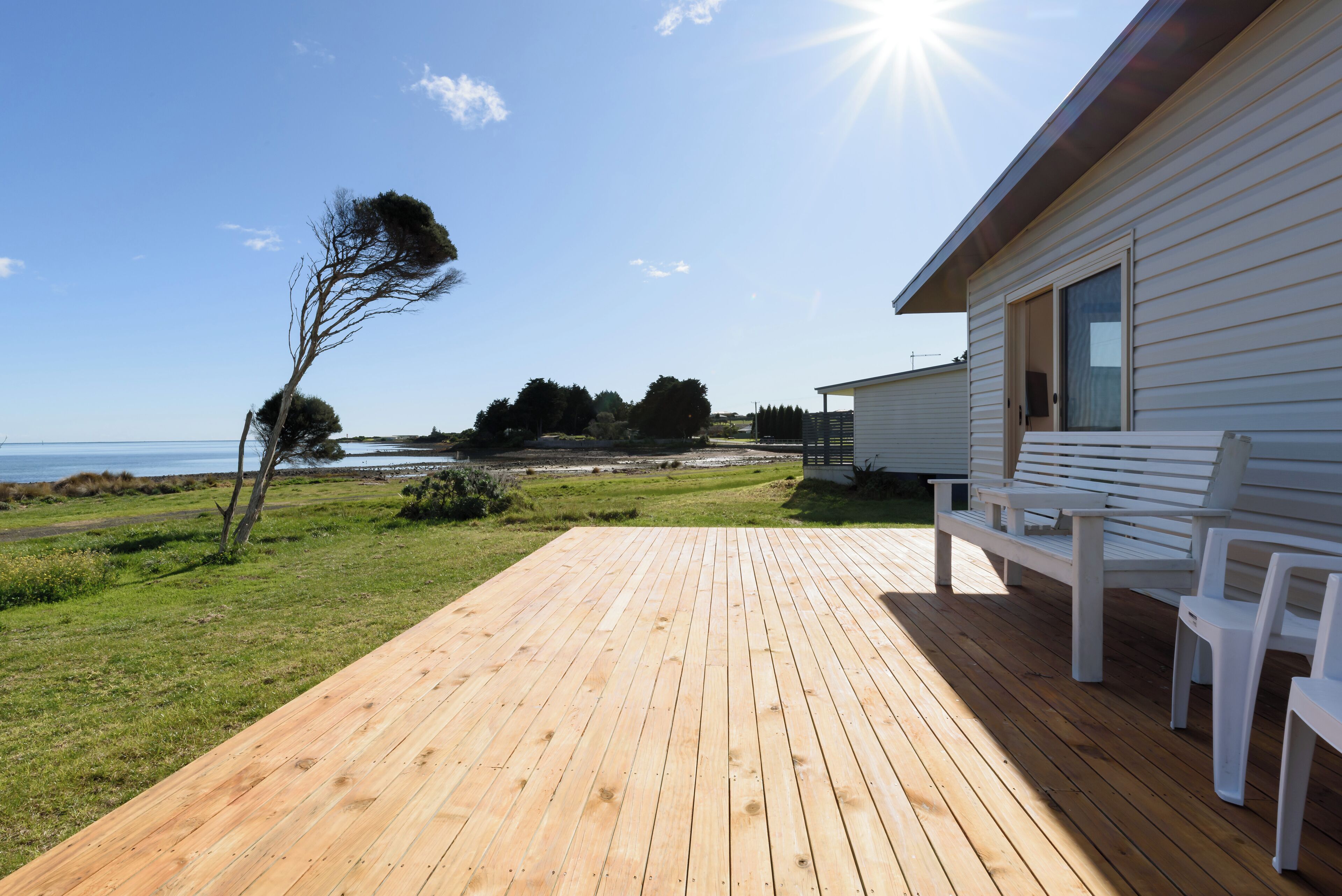 Sunlit wooden deck featuring bench seating and sweeping vistas of the river and ocean.