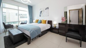 Una habitación de hotel moderna con una cama grande, un escritorio, una silla y vistas a la ciudad.