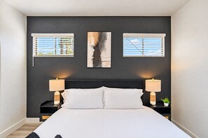 A bedroom with a bed, two bedside tables with lamps, and three windows with blinds. - 3Min To Stadium w/ Balcony Pool Gym Parking W/D (Glendale)