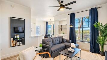 A modern living room with a sofa, a coffee table, and a TV mounted on the wall.