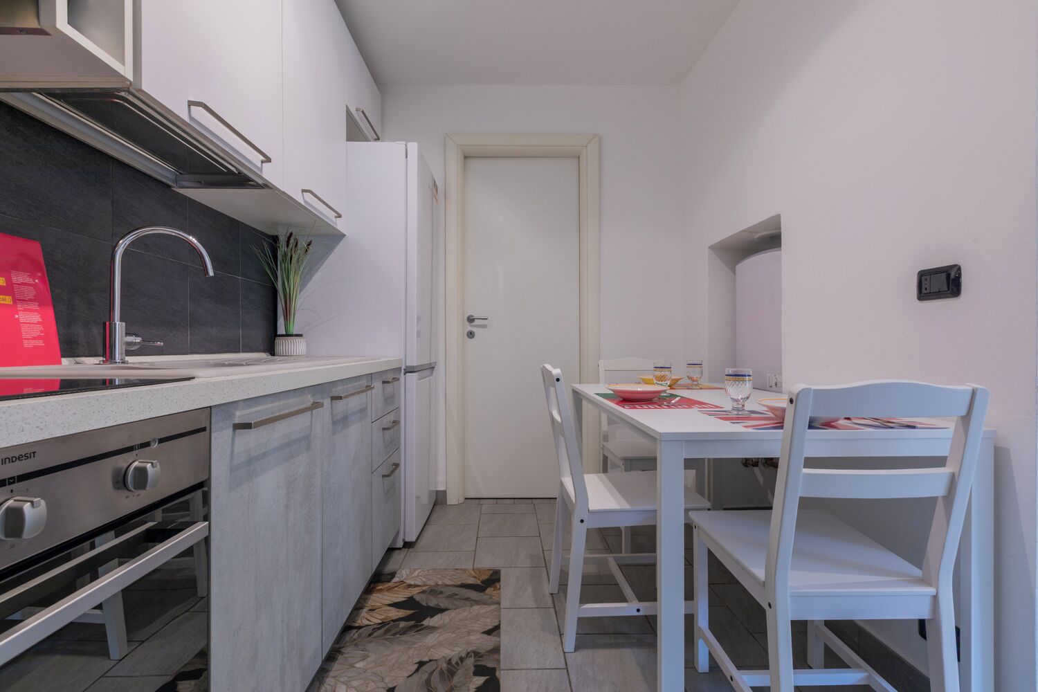 A compact kitchen with white cabinets, a stainless steel stove, and a dining area with a table and chairs.