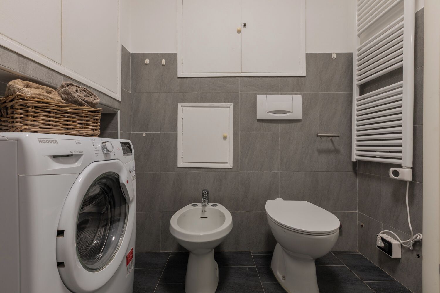 Une petite salle de bain équipée d’un lave-linge à chargement frontal, d’un lavabo sur colonne et de toilettes.