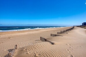 En strand med et træhegn og en bygning i baggrunden.