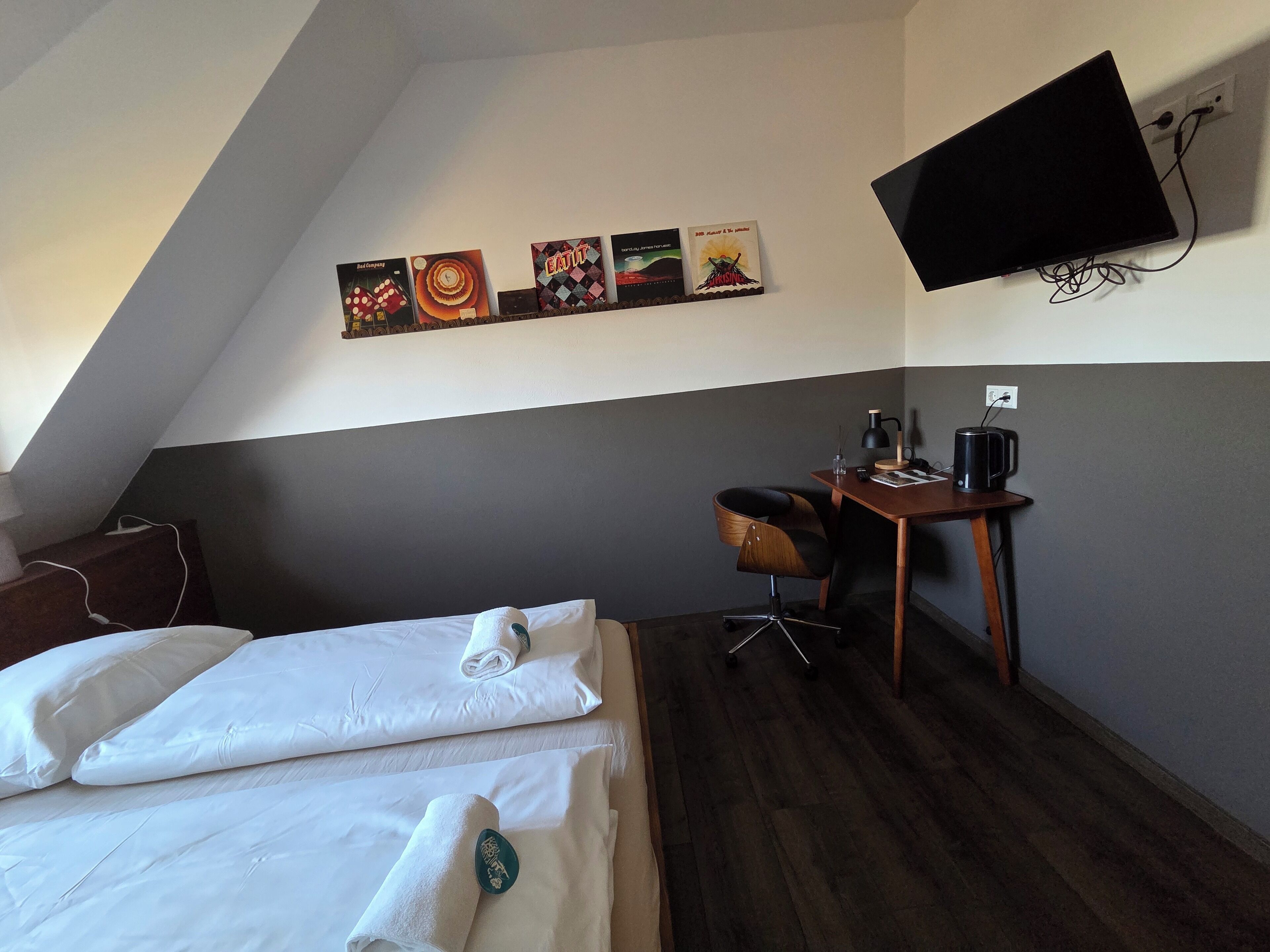 Habitación de hotel con dos camas, un escritorio, una silla, un televisor de pantalla plana y una obra de arte en la pared.