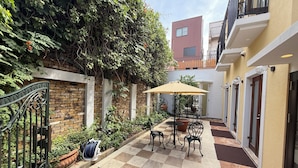 A courtyard with a checkered floor, a table with chairs, and potted plants. - Gouhou Garden Hotel (Tokyo)