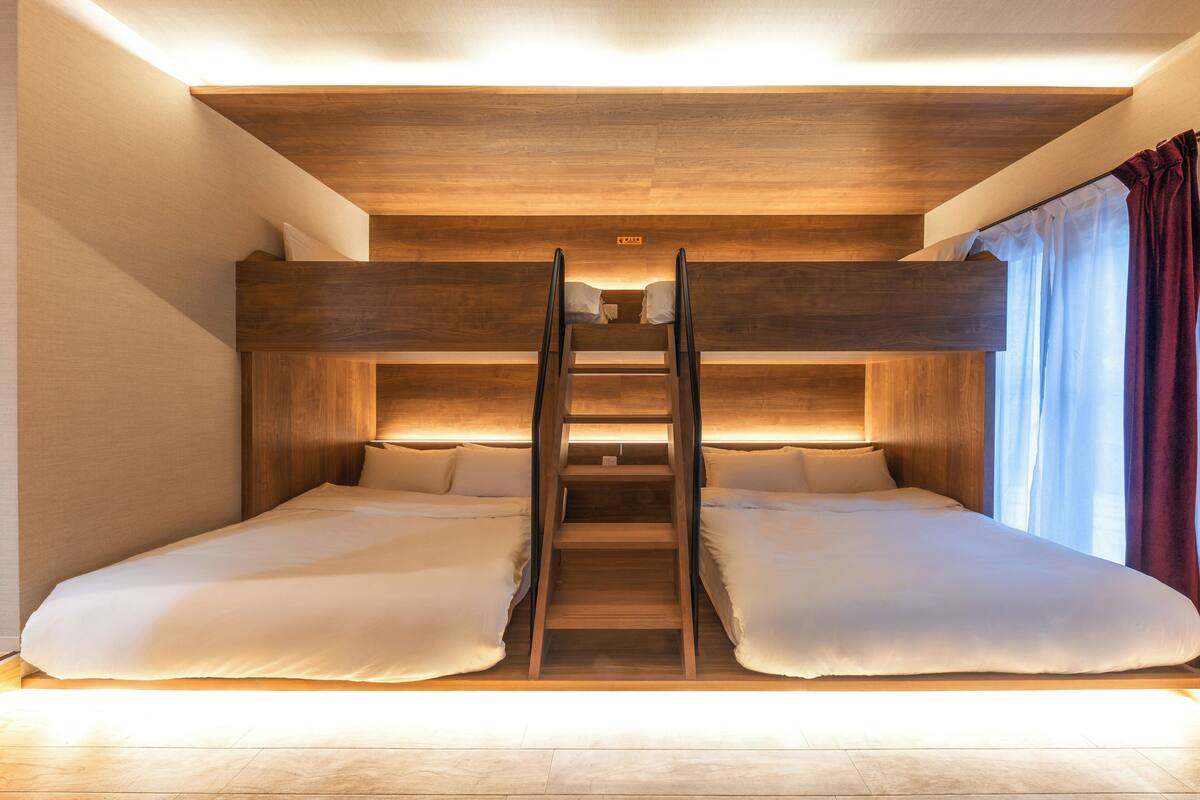 A bunk bed with a ladder, wooden headboard, and white bedding.