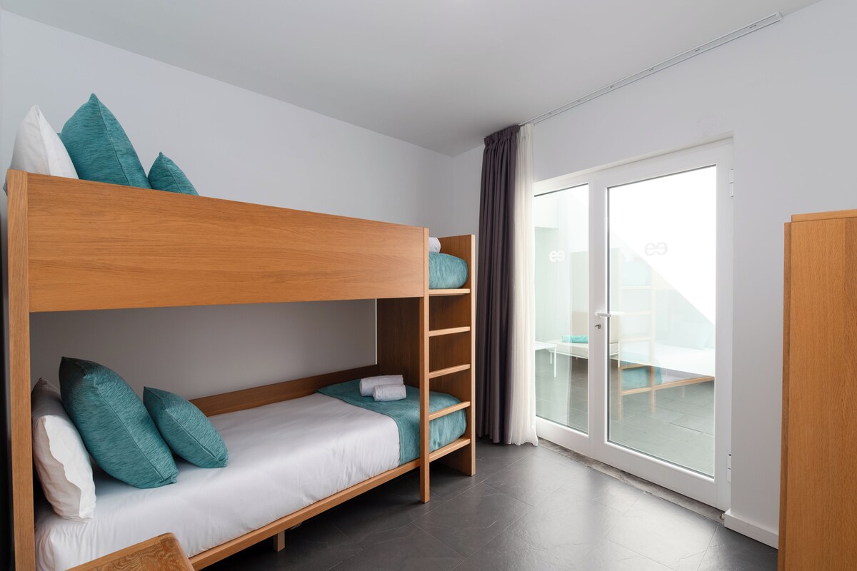 A bunk bed room with a sliding glass door leading to an outdoor area.