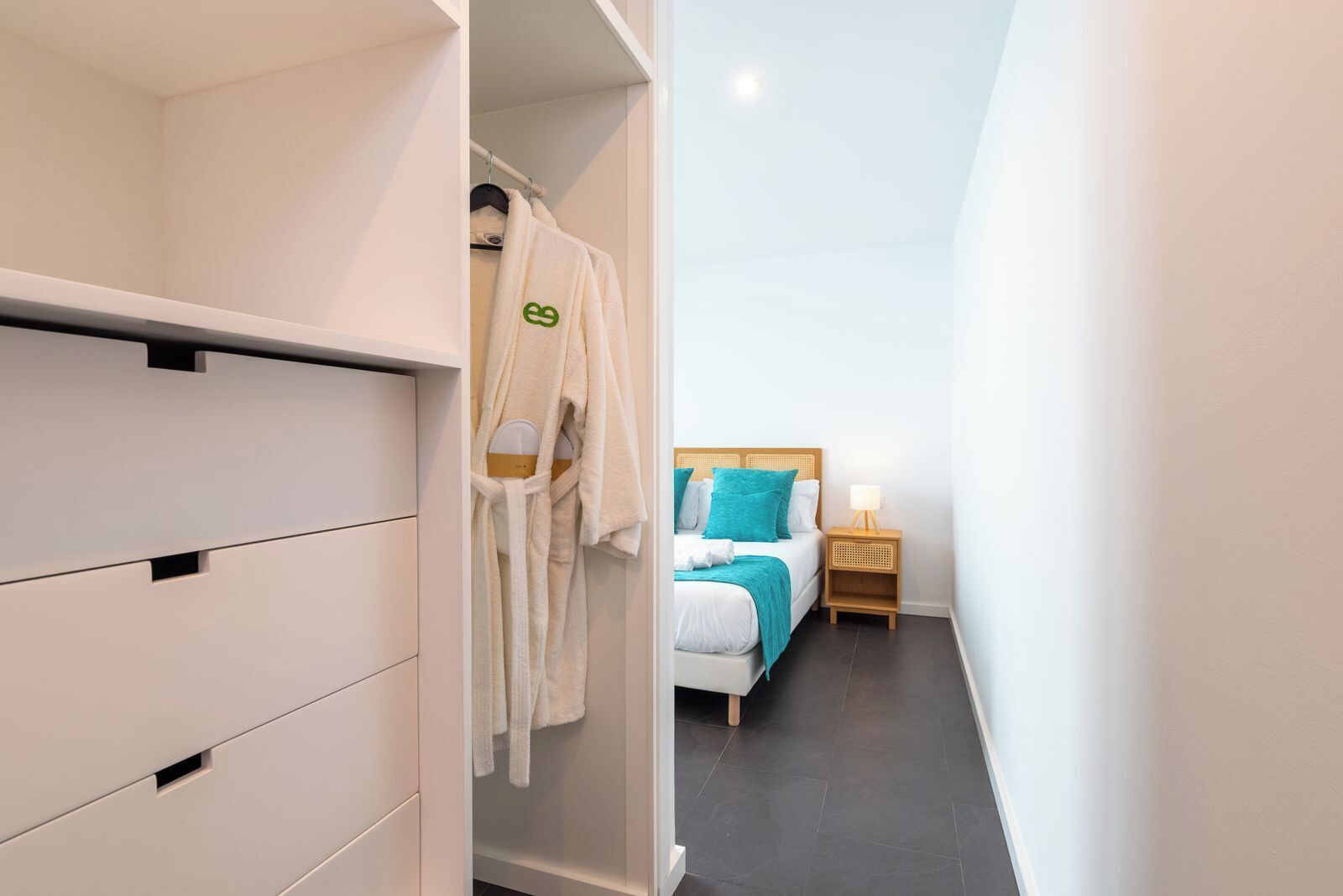 A hotel room with a bed, bedside table, and a wardrobe.