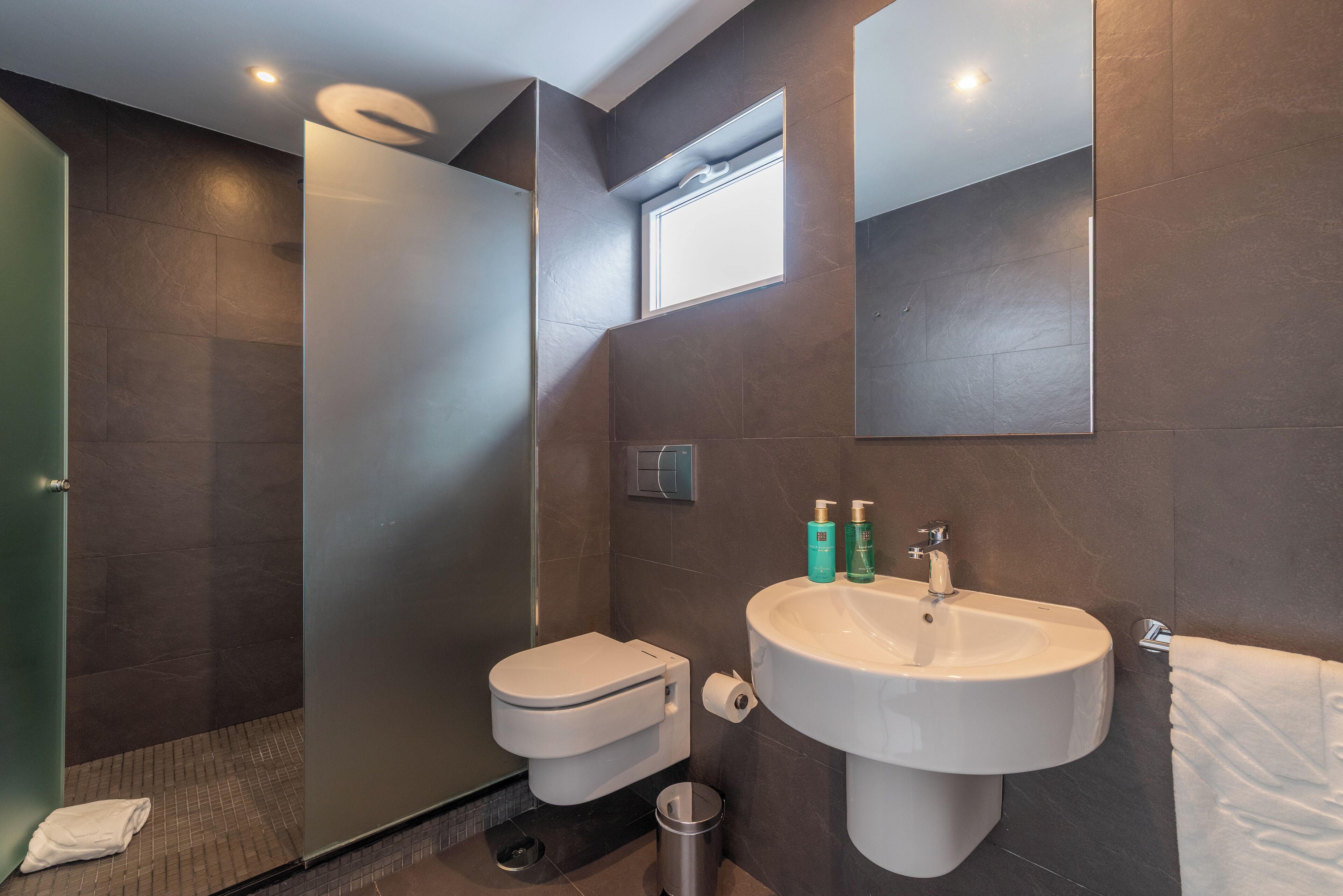Ein modernes Badezimmer mit Dusche, Toilette, Waschbecken und Handtuchhalter.