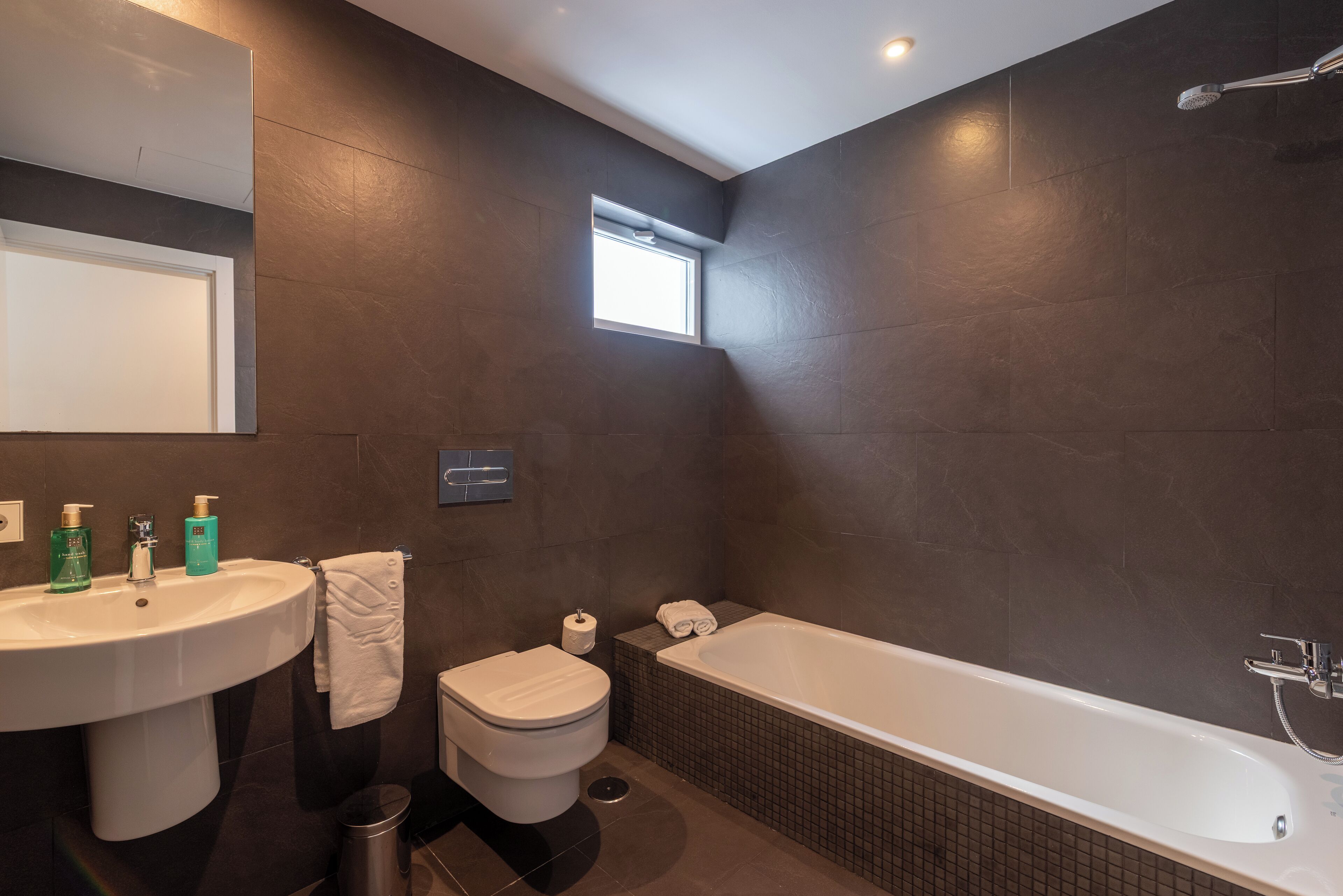 A modern bathroom with a large bathtub, a sink, and a toilet.