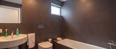 A modern bathroom with a large bathtub, a sink, and a toilet.