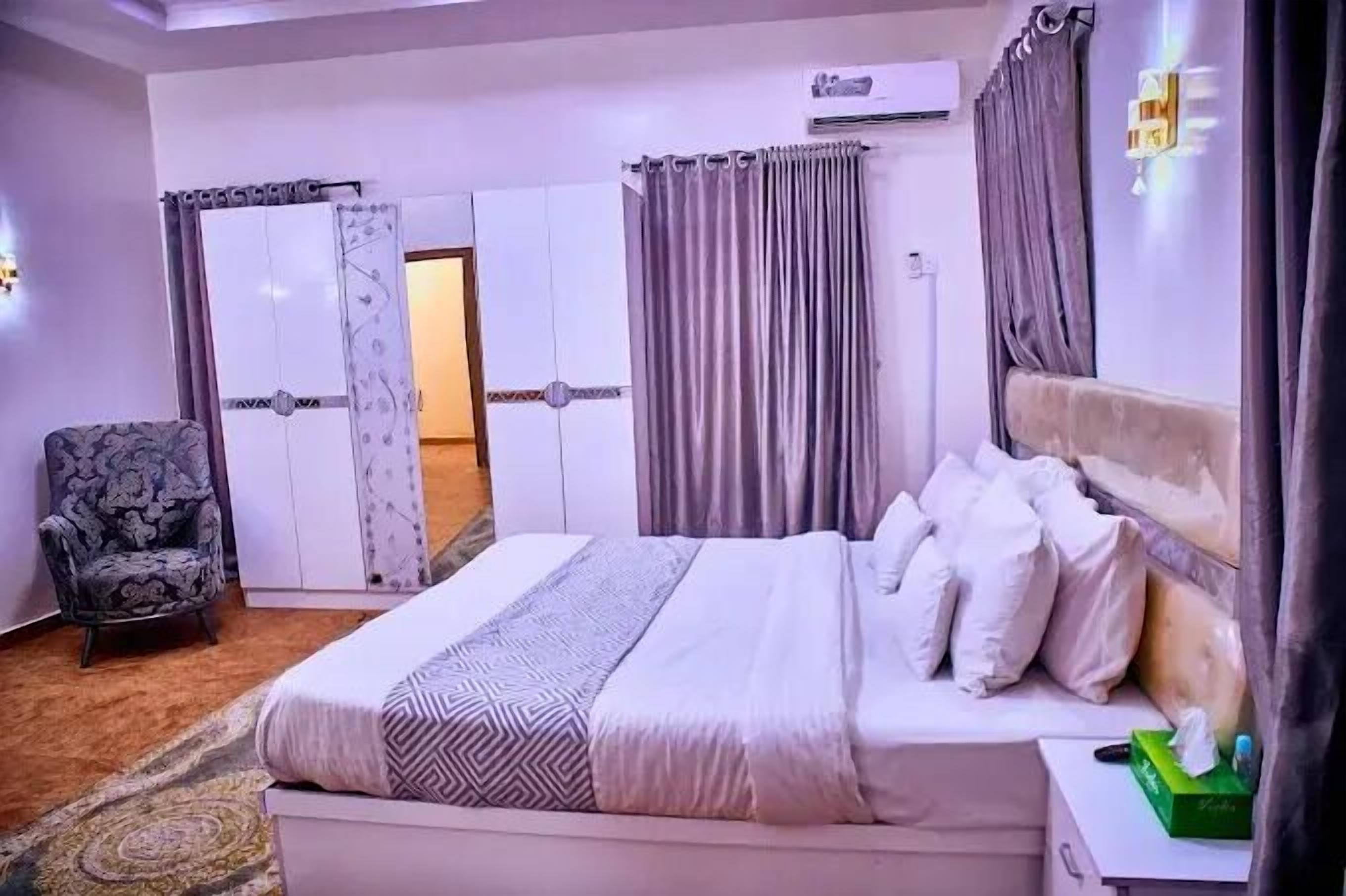 A bedroom with a bed, a chair, and a wardrobe.