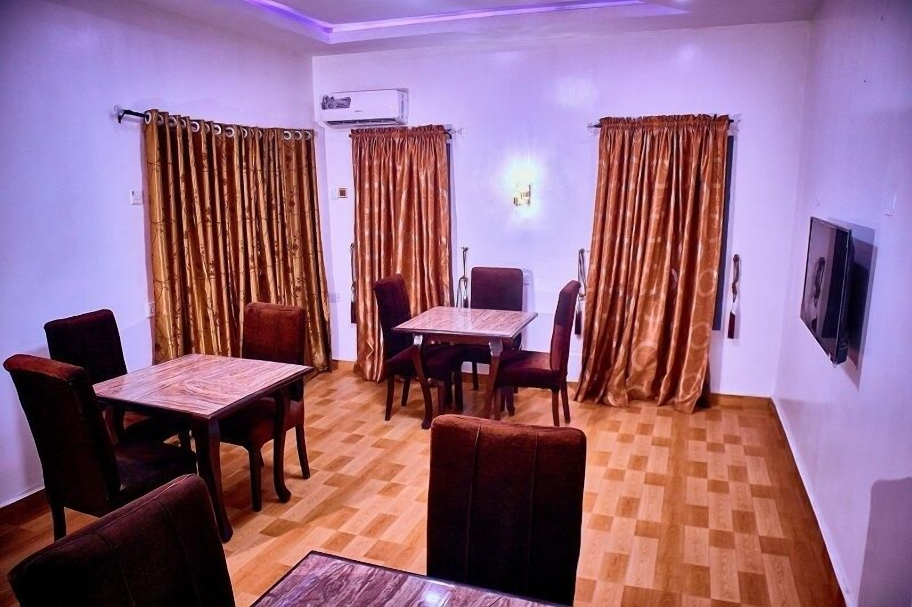 A dining area with a wooden table and chairs, air conditioning unit, and curtains.