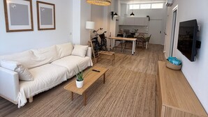 A modern living room with a sofa, coffee table, and a dining area with chairs and a table.