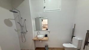 A compact bathroom with a shower, sink, and toilet.