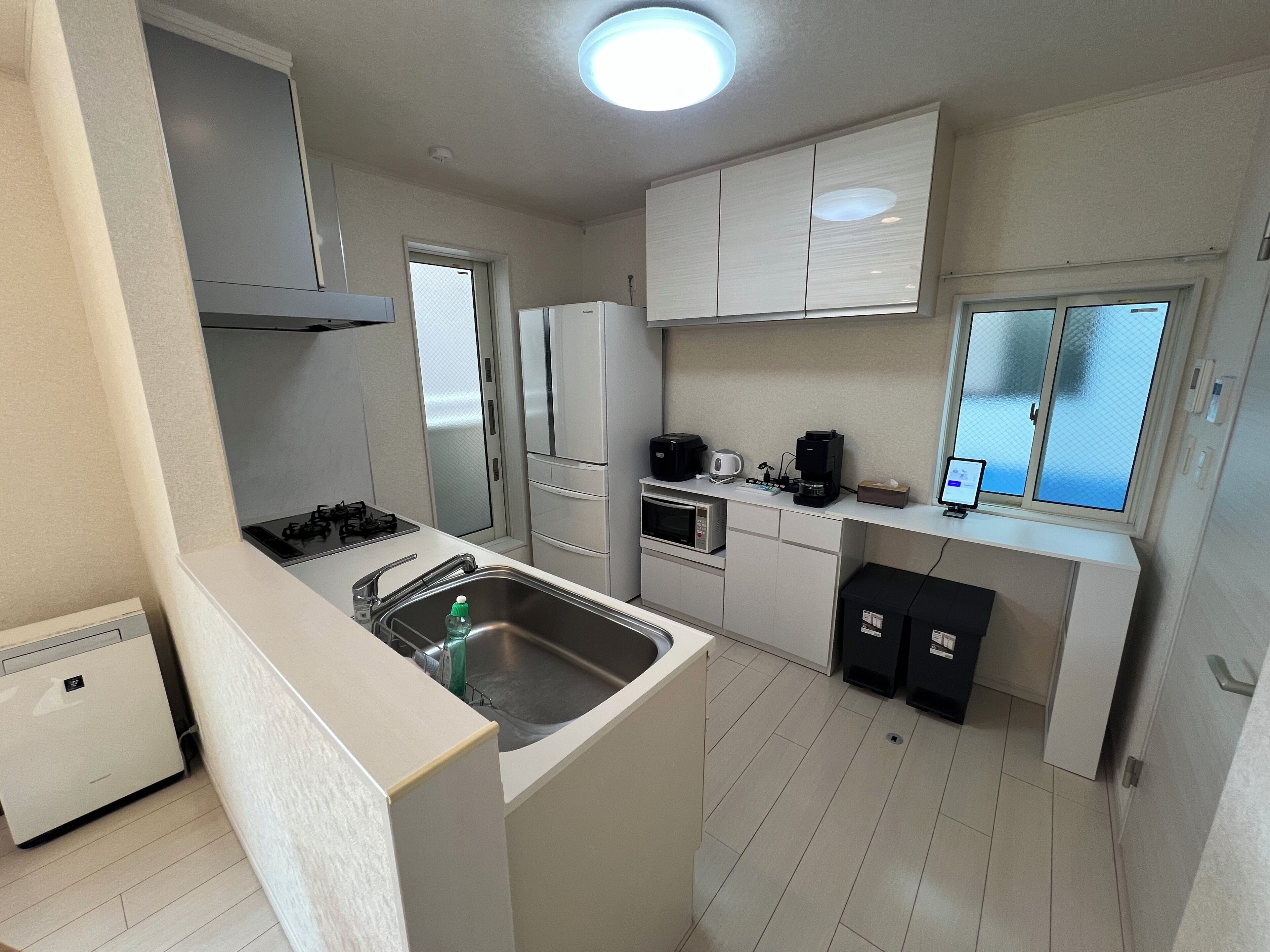 A compact kitchen with a sink, stove, microwave, refrigerator, and a small coffee maker.
