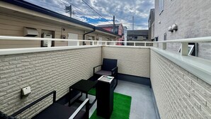 A narrow alleyway with a brick wall, a small table, and a chair. There are buildings on both sides, and a power line is visible above. - COREHOTEL Ikebukuro (Tokyo)