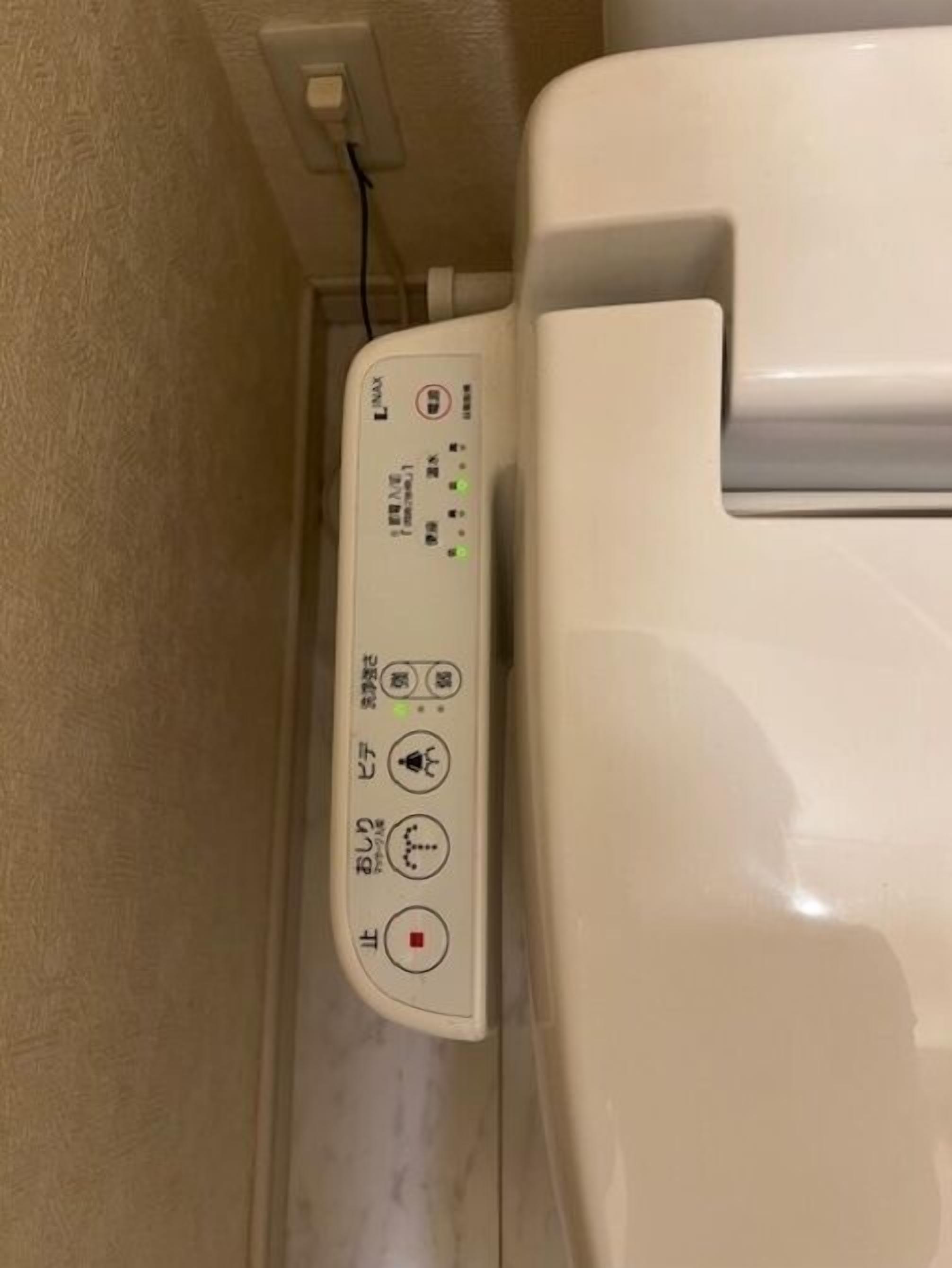 A white toilet with a control panel featuring Japanese text and symbols.