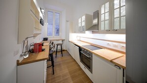 A compact kitchen with a wooden countertop, a built-in oven, and a window with blinds. - Lilla Home (Roma)