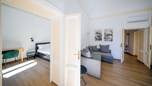 A modern living room with a sofa, a desk, and a bed. - Lilla Home (Roma)