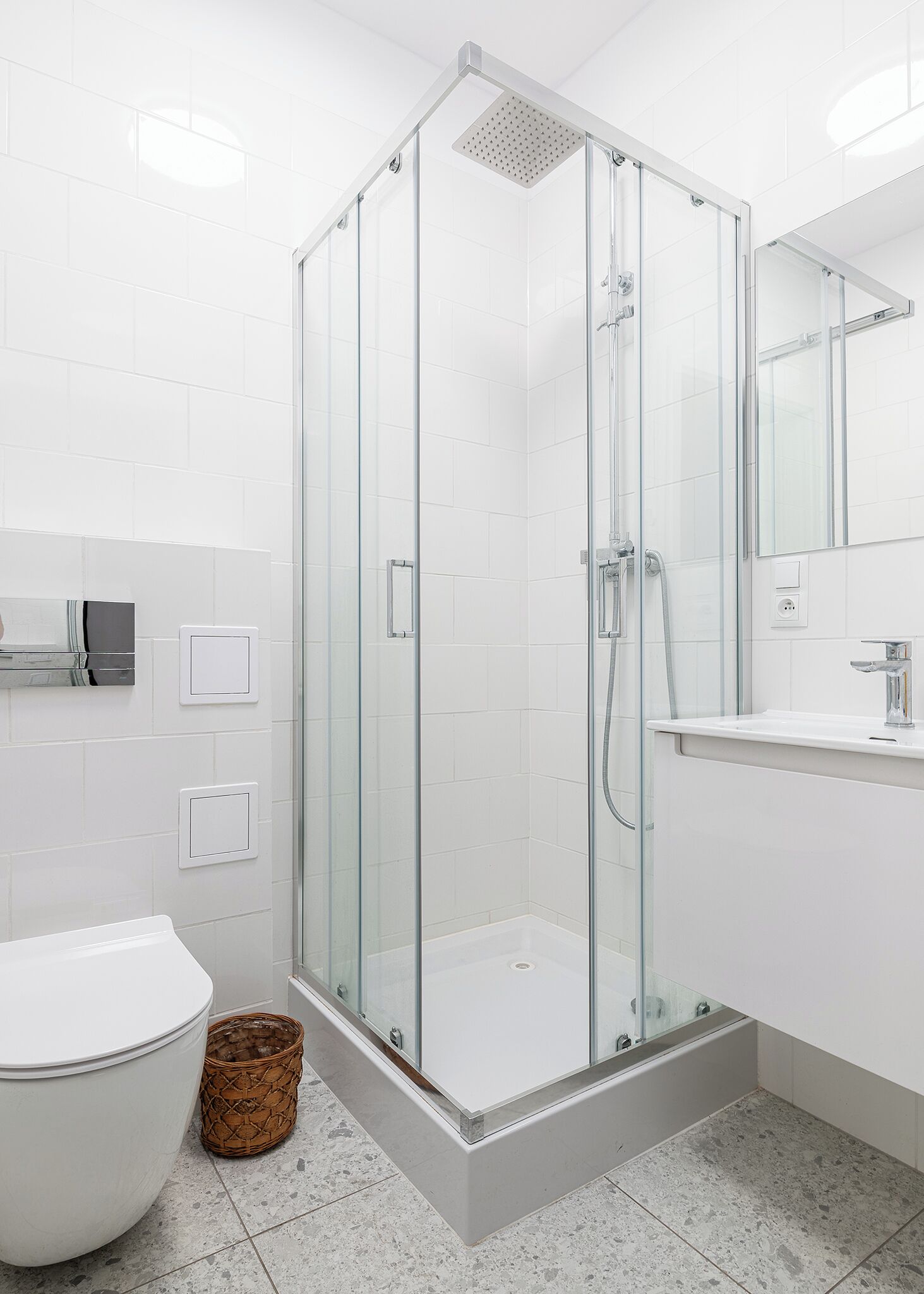 Un baño moderno con ducha envuelta en vidrio, inodoro y lavabo con espejo.