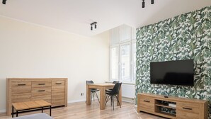 Ein modernes Wohnzimmer mit einer Holzkabine, einem an der Wand montierten Fernseher und einem Fenster mit Jalousien.