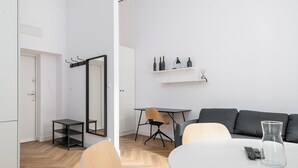 Ein modernes Wohnzimmer mit einem weißen Tisch, einem schwarzen Sessel, einem grauen Sofa und einer Glasvase.