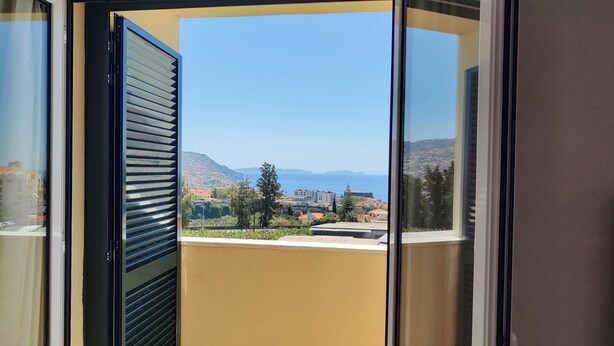 A balcony with a view of a coastal town and mountains.