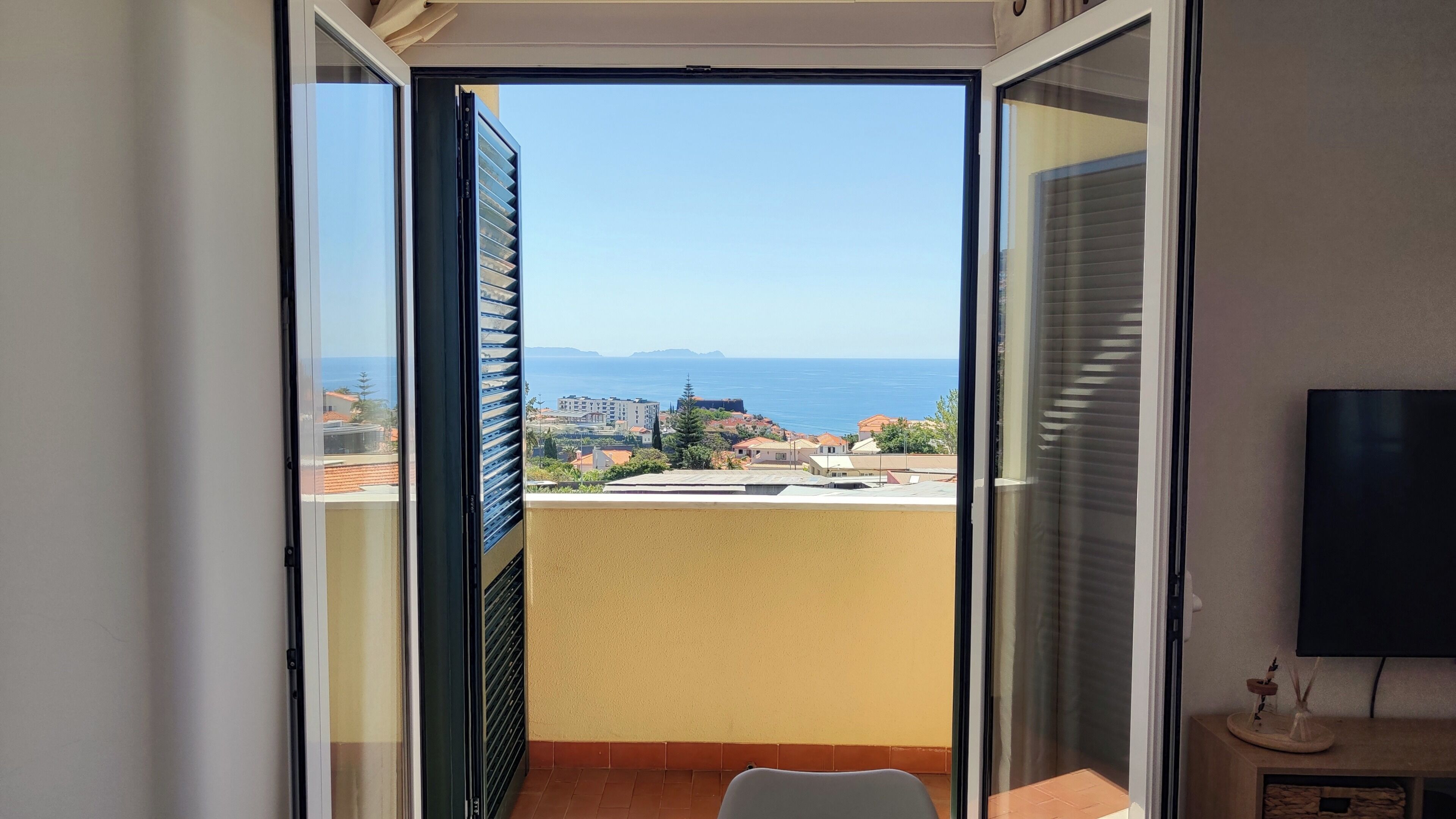 A balcony with a view of the sea and buildings.