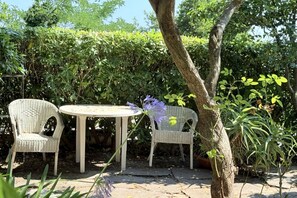 A garden area with two wicker chairs and a small round table.