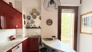 A kitchen with a marble countertop, red cabinets, a sink, and a dining area with chairs.