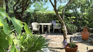 An outdoor patio with wicker chairs, a round table, and potted plants.