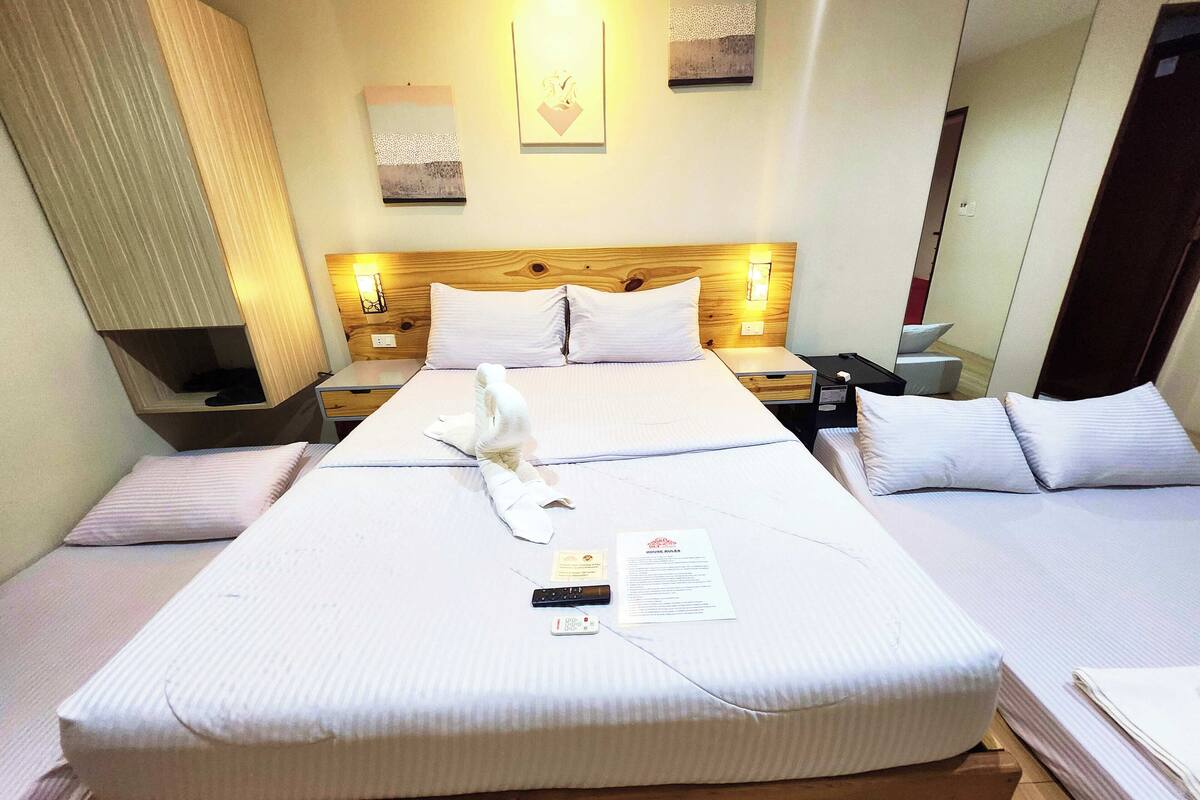 A hotel room with a large bed, two bedside tables, a nightstand, and a mirror.