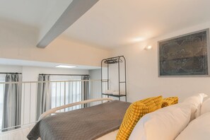 A bedroom with a bed, a window with curtains, a wall-mounted shelf with towels, and a painting. - Architect's Loft by Rent all Como (Como)