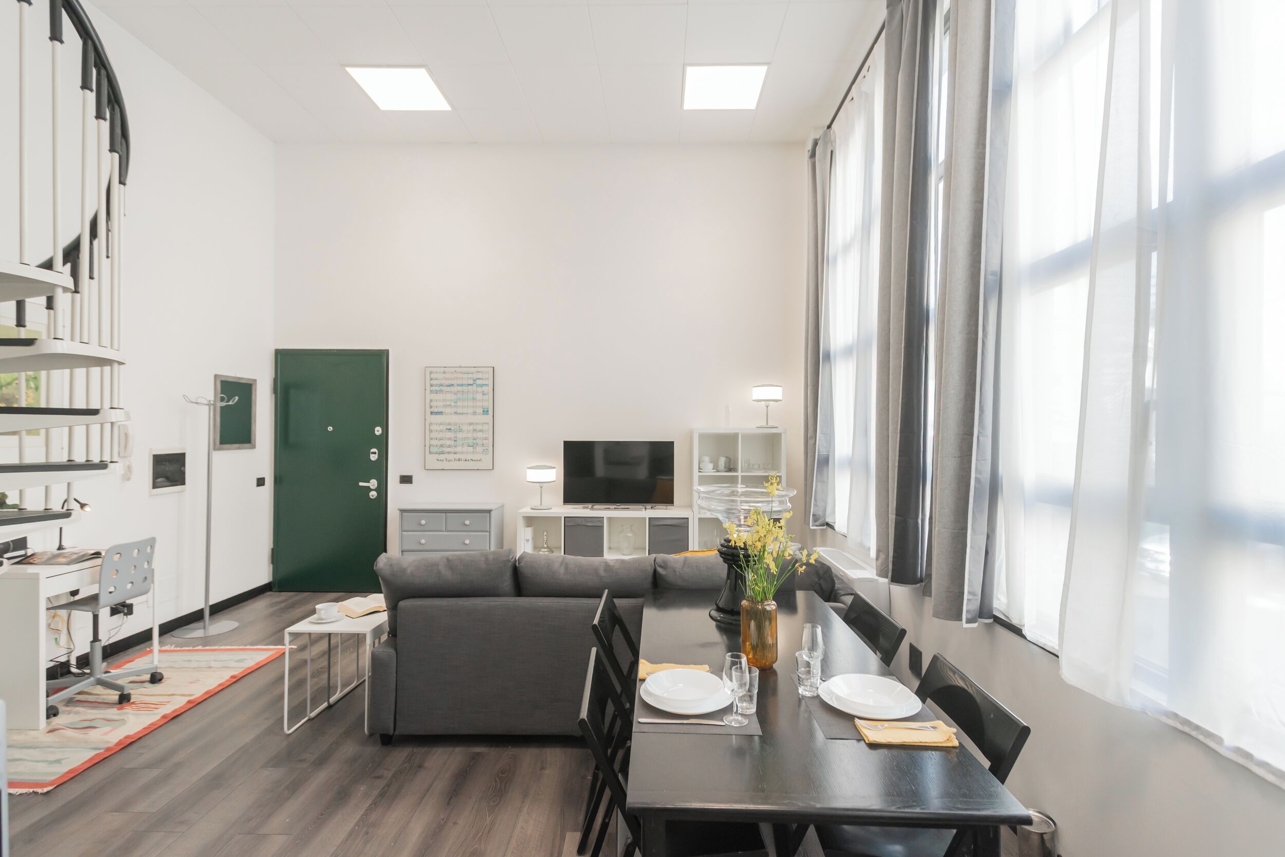 A modern living room with a sofa, dining table, and a TV in the background.