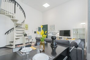 A modern living room with a staircase, a dining area, and a TV. - Architect's Loft by Rent all Como (Como)
