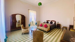 A room with a checkered floor, a bed with pillows, a wooden wardrobe, a mirror, and a green hanging light fixture. - Domus Evora - Period home in the historic center (Tropea)