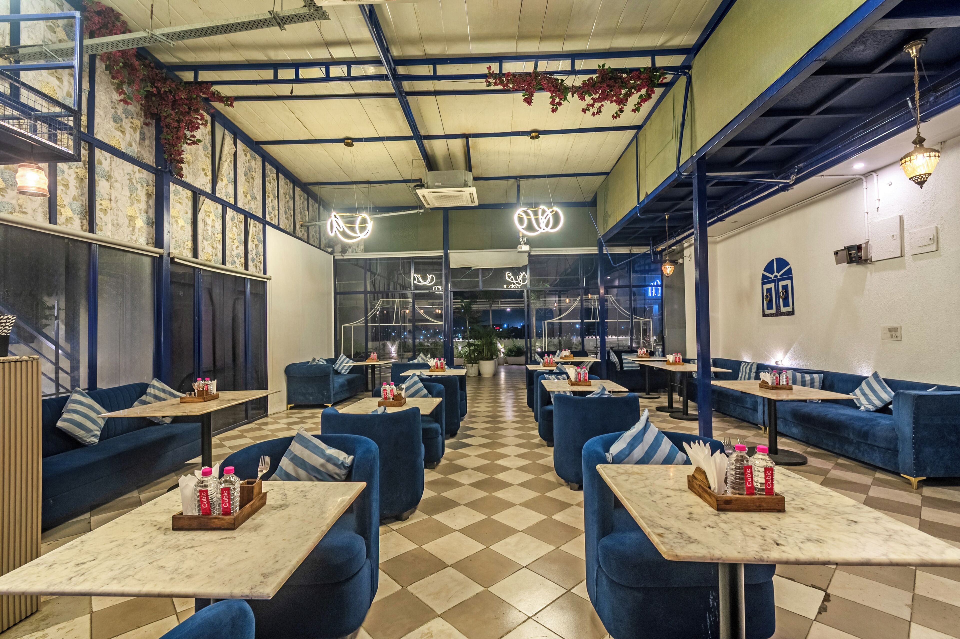 Un restaurant avec des canapés bleus, des revêtements de sol à carreaux et des tables où l’on trouve des condiments.