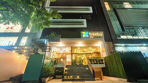 A modern building with a 'treebo' sign, featuring a staircase, glass facade, and indoor plants. - Treebo Viennahttps://apps.expediapartnercentral.com/ (Jaipur)