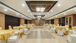 A banquet hall with rows of tables and chairs, each covered with white tablecloths and yellow sashes. - Treebo Viennahttps://apps.expediapartnercentral.com/ (Jaipur)