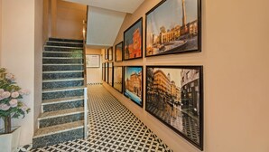 A hallway with a staircase, framed pictures on the wall, and a patterned floor. - Treebo Viennahttps://apps.expediapartnercentral.com/ (Jaipur)