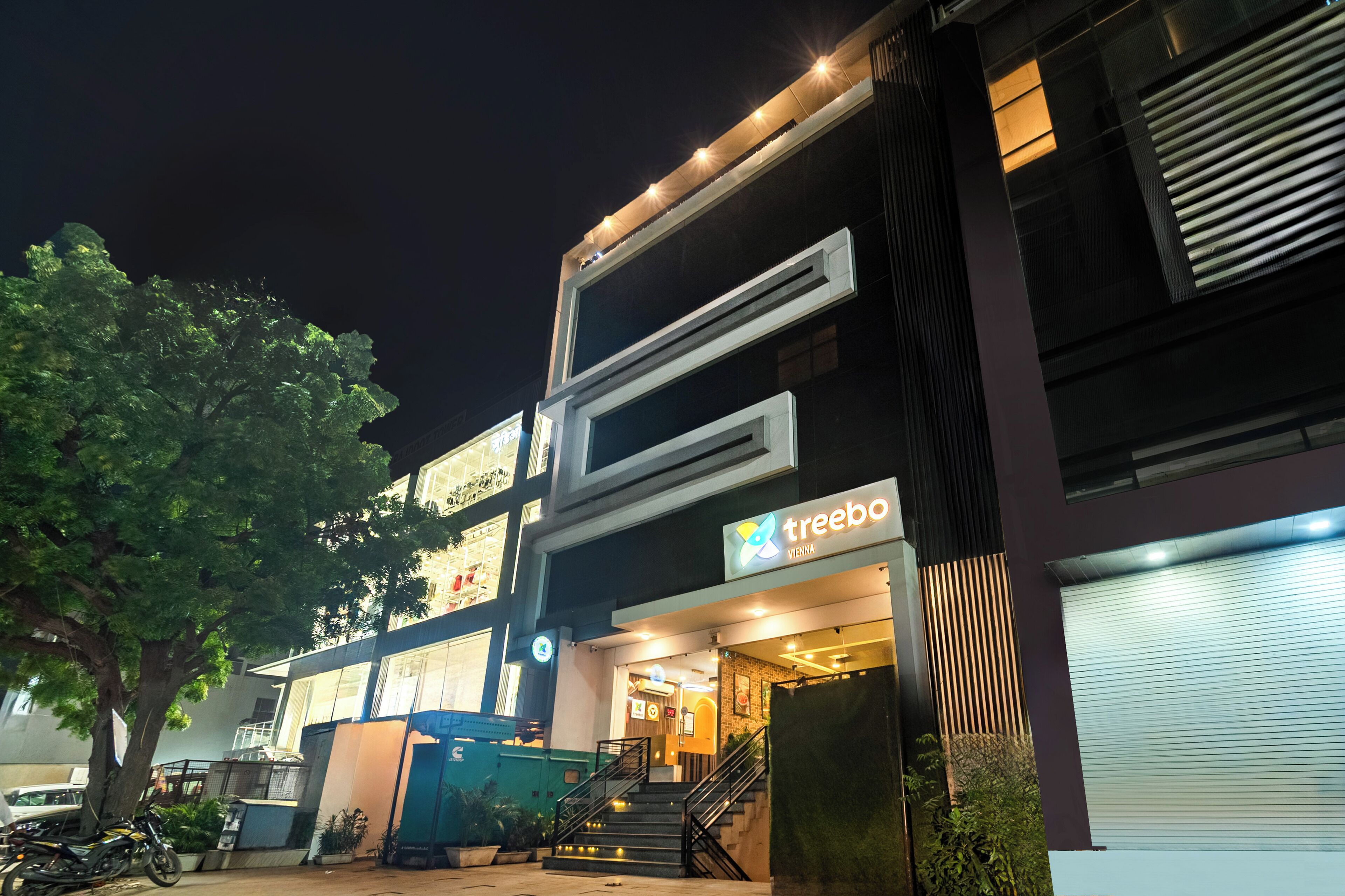 A modern building with a 'treeba' sign, a staircase, and a tree in front.