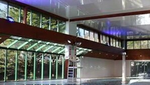 A large indoor swimming pool with clear glass walls and a modern design. - Casita De Cuervo at Country Park (Lymington)